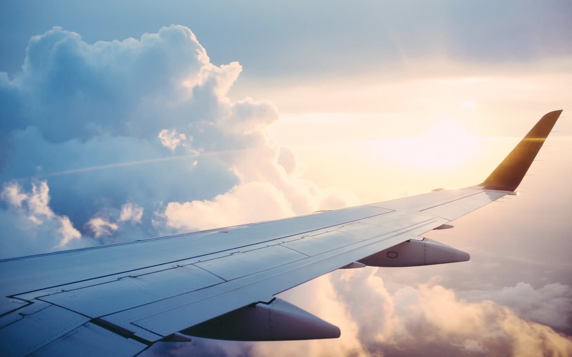 An airplane wing above the clouds during a business trip